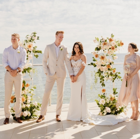 water venue, orange and blush flowers, blue skies for ceremony